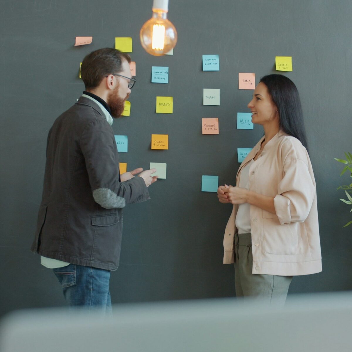 Two colleagues talking at a wall of sticky notes